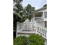 Charming home entrance featuring a wooden porch with white railings and lush greenery at 3701 Shallowford Rd, Marietta, GA 30062