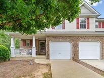 Charming townhome featuring a covered porch, two-car garage, and brick and vinyl siding at 138 Fox Creek Dr, Woodstock, GA 30188