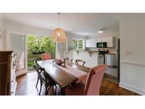 Bright dining room featuring a long wood table, pendant lighting and French doors to outdoor balcony at 115 Peachtree Memorial Nw Dr # C1, Atlanta, GA 30309