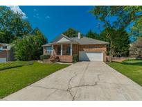 Charming single Gathering home featuring a well-manicured lawn and long concrete driveway at 135 Greenmont Downs Trce, Alpharetta, GA 30009