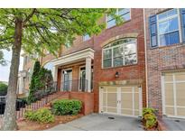 Charming brick townhome featuring an attached garage, a welcoming front porch and professional landscaping at 10898 Gallier St, Johns Creek, GA 30022
