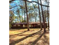 Quaint single-story home nestled among tall trees, offering a private and serene setting at 4212 Moore Rd, Conley, GA 30288
