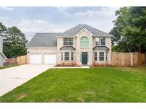 Charming two-story home with a well-manicured lawn, brick facade, and a two-car garage at 1976 Glen Echo Dr, Decatur, GA 30032