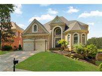 Beautiful brick home with a well-manicured lawn, two-car garage, and stunning architectural details at 5335 Davenport Mnr, Cumming, GA 30041
