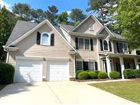 Charming home featuring a two-car garage, manicured shrubs, and a well-maintained front lawn at 6131 Windflower Dr, Powder Springs, GA 30127