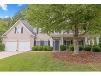 Charming two-story home with a manicured lawn, mature trees, and a welcoming front porch with beautiful landscape at 6131 Windflower Dr, Powder Springs, GA 30127