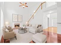 Bright living room featuring high ceilings, a cozy fireplace, and an elegant staircase leading to the upper level at 6131 Windflower Dr, Powder Springs, GA 30127