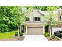 Charming two-story home with a brick facade and an attached two-car garage surrounded by mature trees at 2450 Norwood Park Xing, Atlanta, GA 30340