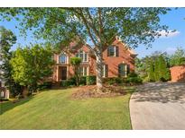 Charming brick home with well-manicured lawn, mature trees, and inviting curb appeal on a sunny day at 6020 Ettington Dr, Suwanee, GA 30024