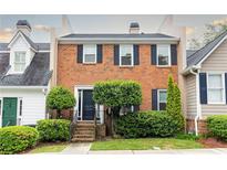 Charming brick townhouse featuring black shutters, well-manicured landscaping, and welcoming front entrance at 911 Lenox Hill Ne Ct, Atlanta, GA 30324