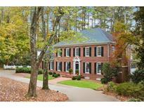 Charming brick two-story home with black shutters, mature landscaping, and a circular driveway surrounded by colorful trees at 769 Hampton Sw Pl, Marietta, GA 30064