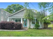 Charming home featuring fresh landscaping and a welcoming front porch with light blue door and trim at 1283 Mercer Ave, East Point, GA 30344