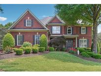 Beautiful red brick home with mature landscaping and a well-manicured lawn at 6640 Stratford Pl, Cumming, GA 30040