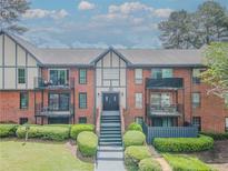 Charming condo building with brick facade, black trim, and balcony access on the second floor at 6851 Roswell Rd # 0-26, Atlanta, GA 30328