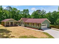 Ranch-style home features an attached garage, a large yard, and a lovely setting surrounded by lush greenery at 3340 Zingara Rd, Conyers, GA 30012