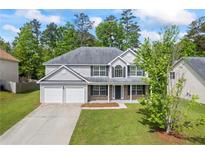 Charming two-story home featuring a well-manicured lawn, attached two-car garage, and traditional architectural details at 6895 Smoke Ridge Dr, Atlanta, GA 30349