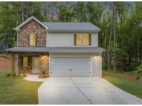 Charming two-story home featuring a stone facade, light siding, and an attached two-car garage in a lush, wooded setting at 191 Davis Ct, Hiram, GA 30141