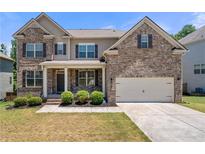 Charming two-story brick home featuring a welcoming front porch and well-manicured landscaping at 5465 Mirror Lake Dr, Cumming, GA 30028