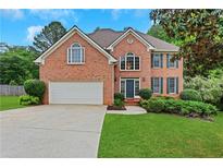 Charming brick home with well-manicured lawn, two-car garage, and inviting front entrance at 5435 Vicarage Walk, Alpharetta, GA 30005