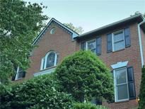 Brick home featuring black shutters, manicured bushes, and a gable accent window at 990 Azalea Dr, Roswell, GA 30075