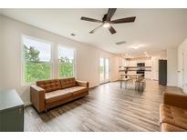 Open-concept living room with modern ceiling fan, wood-style flooring, and bright windows at 33 Oxford Ln, Kingston, GA 30145