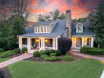 Charming home with a covered porch, stone chimney, manicured landscaping and brick walkway at 11660 Crabapple Rd, Roswell, GA 30075