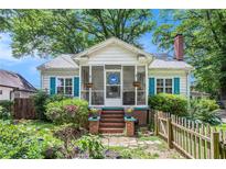 Charming home with a cozy screened front porch, brick steps, lush landscaping, and bright blue shutters at 212 South Se Ave, Marietta, GA 30060