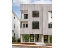 Modern, three-story home with light wood siding, black-framed windows, and a small balcony at 11542 Serenbe Ln, Chattahoochee Hills, GA 30268