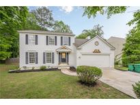 Charming white two-story home with dark shutters and a well-manicured front lawn and attached two car garage at 303 Cimarron Way, Lawrenceville, GA 30044