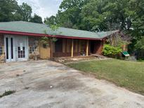 Exterior of the home with a brick and stone facade, covered porch, and dated landscape at 1405 Mote Rd, Covington, GA 30016