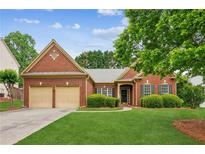 Charming brick home featuring a manicured front lawn and a two-car garage at 1815 Montcliff Dr, Cumming, GA 30041