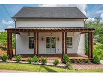 Charming two-story home with a covered front porch, manicured lawn, and brick-lined flower beds at 50 Maple St, Roswell, GA 30075