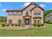 Inviting two-story home featuring a manicured lawn, mature landscaping, and classic architectural details at 105 Tanners Ct, Covington, GA 30016