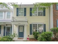 Charming townhome featuring light yellow siding, dark blue shutters, and a small balcony over the entry door at 3746 Berkeley Xing, Duluth, GA 30096