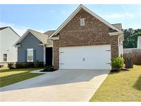 Charming home featuring a two-car garage, brick accents, and a well-manicured lawn at 3785 Newbury Place Dr, Loganville, GA 30052