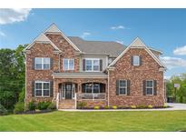 Charming two-story brick home featuring a covered porch and meticulously manicured lawn at 6375 Haystack Ct, Cumming, GA 30040