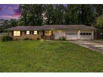 Charming single-story home with brick facade, lush lawn, and attached two-car garage at 1239 Sharonton Dr, Stone Mountain, GA 30083