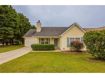 Charming yellow home with blue shutters, green lawn and mature trees at 4045 Meadow Glen Way, Fairburn, GA 30213