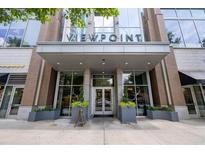 Elegant condo building entrance with glass doors, brick accents, and stylish planters for a welcoming arrival at 855 Peachtree Ne St # 2713, Atlanta, GA 30308