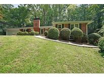 Charming brick home featuring a neat front yard and mature trees, creating a welcoming curb appeal at 6835 Castleton Dr, Sandy Springs, GA 30328