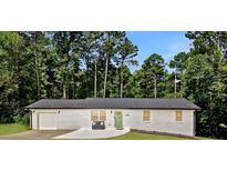 Charming white brick house with a green door and a well-manicured lawn surrounded by lush trees at 101 Stroud Se Dr, Mableton, GA 30126
