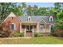 Charming brick home with stone accents, a covered porch, blue shutters, and a well-maintained lawn at 1590 Johnson Ne Rd, Atlanta, GA 30306