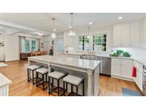 Bright kitchen featuring white cabinets, hardwood floors, stainless appliances, large island with bar seating, and open floor plan at 1590 Johnson Ne Rd, Atlanta, GA 30306