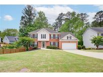 Charming two-story brick home with a well-maintained lawn and attached two-car garage at 1812 Riverton Dr, Suwanee, GA 30024