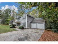 Two-story home featuring a two-car garage, gray siding, and a well-maintained front lawn at 565 Lake Joyce Ln, Fairburn, GA 30213