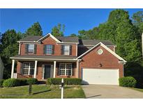 Charming two-story brick home featuring a covered front porch and a two car garage in a suburban neighborhood at 7491 Hilltop Way, Atlanta, GA 30349