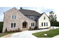 Stunning brick and stone home with manicured lawn and concrete driveway at 5753 Brendlynn Dr, Suwanee, GA 30024