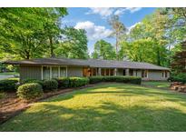 A charming single-story home featuring a well-manicured lawn, mature trees, and stone accents on the facade at 170 Mark Nw Trl, Sandy Springs, GA 30328