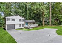 Inviting home with a two-car garage, a wide driveway, and a charming porch amidst lush greenery at 353 Old Rosser Rd, Stone Mountain, GA 30087