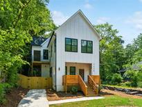 Inviting two-story home with modern farmhouse design, featuring a charming wood porch and lush greenery at 2438 2Nd Nw St, Atlanta, GA 30318